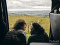 Smiling women sitting in van and looking at landscape