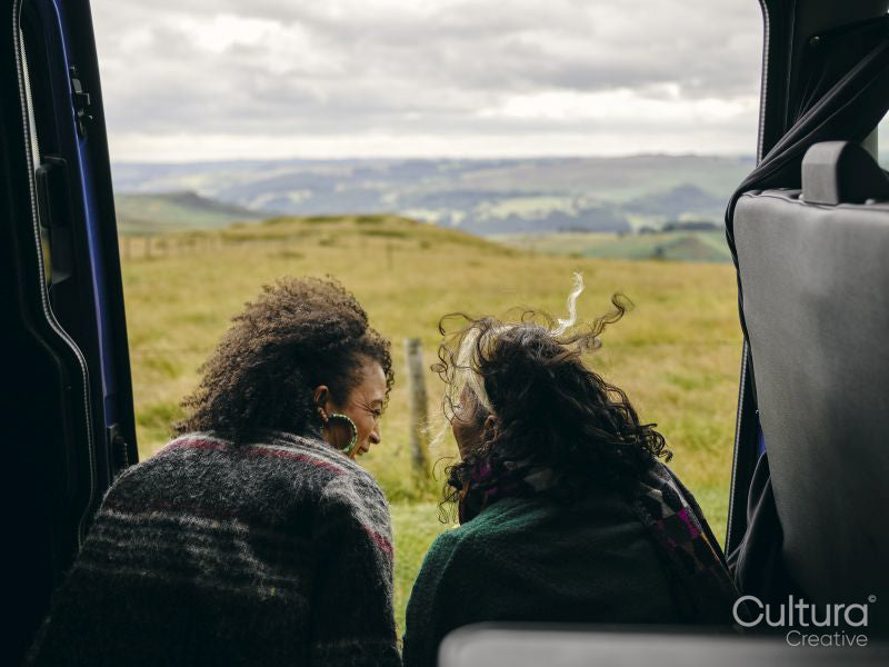Smiling women sitting in van and looking at landscape
