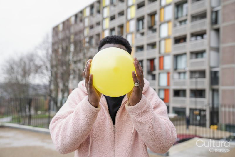 Young man holding balloon in front of face
