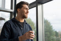 Businessman drinking coffee and looking through office window