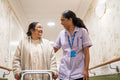 Nurse helping senior lady to walk with mobility walker at nursing home