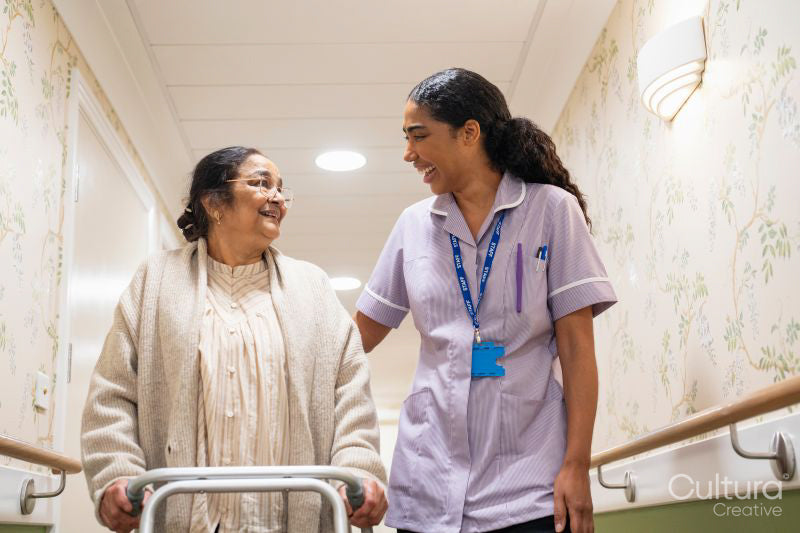 Nurse helping senior lady to walk with mobility walker at nursing home