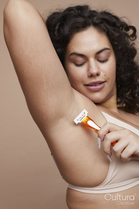 Studio shot of young woman shaving armpits