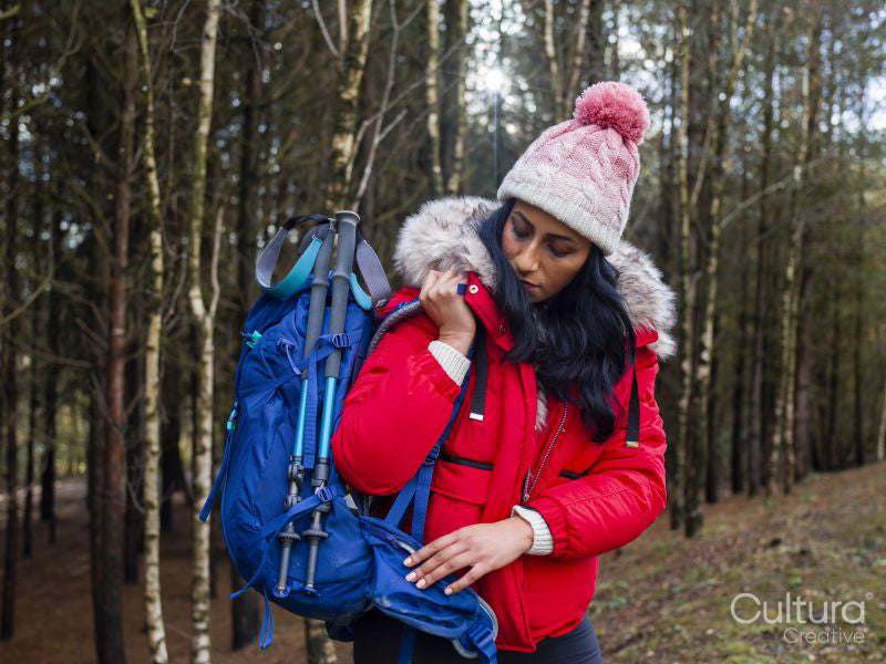 Female hiker putting on backpack