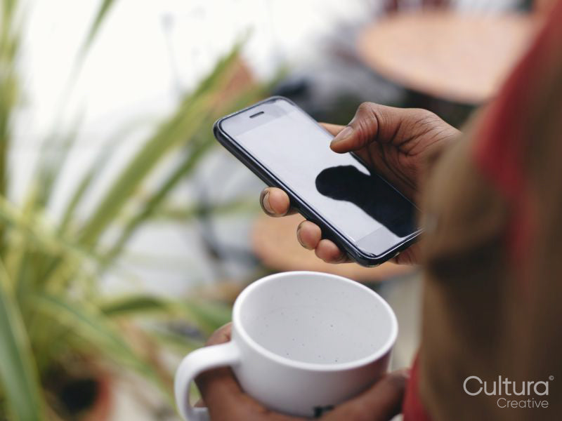 Close-up of mans hands holding smart phone and mug
