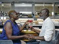 Mature couple enjoying cocktails and holding hands at bar counter