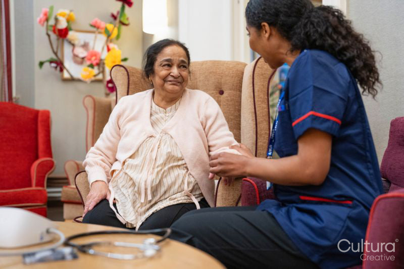 Nursing assistant using pulse oximeter on senior woman at nursing home