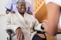 Female doctor talking to senior woman sitting in wheelchair in doctors office