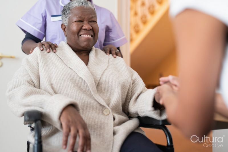 Female doctor talking to senior woman sitting in wheelchair in doctors office