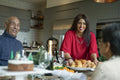 Smiling woman serving roasted turkey to family at table