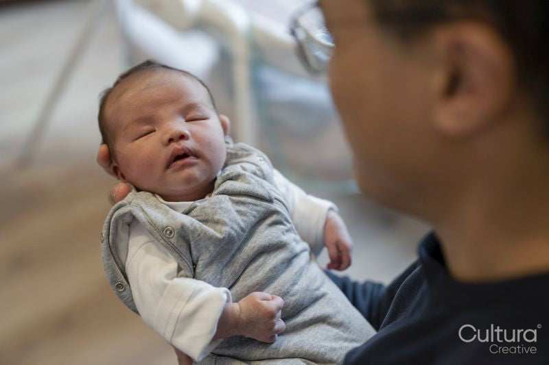 Father holding sleeping baby daughter