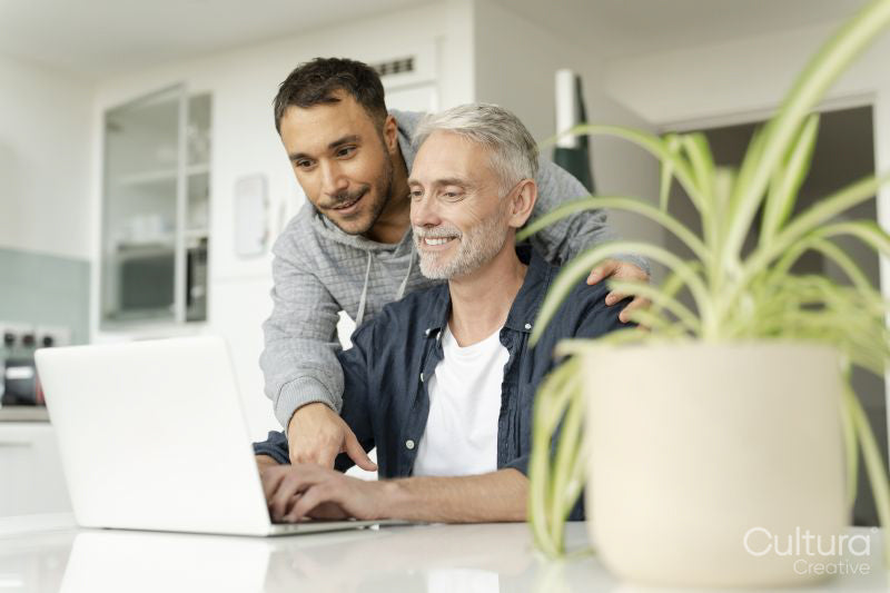 Male couple using laptop at home