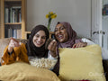 Laughing friends eating popcorn and watching TV at home