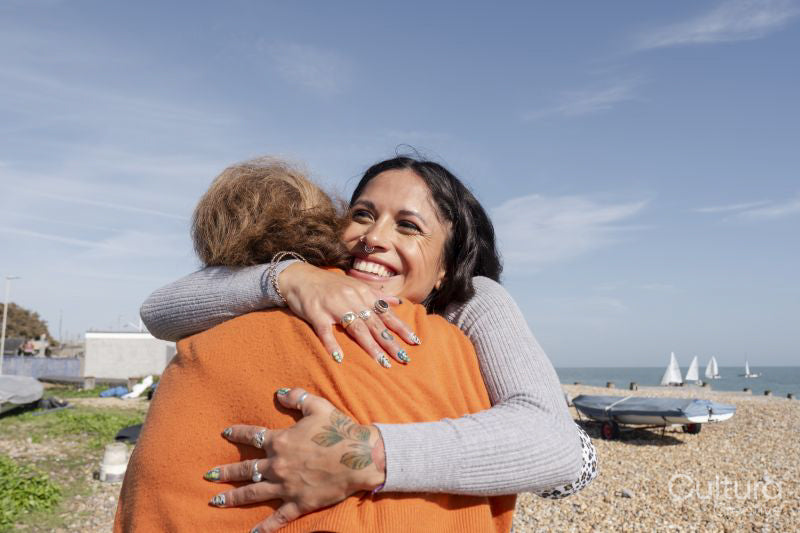 Mother and daughter embracing on beach on sunny day
