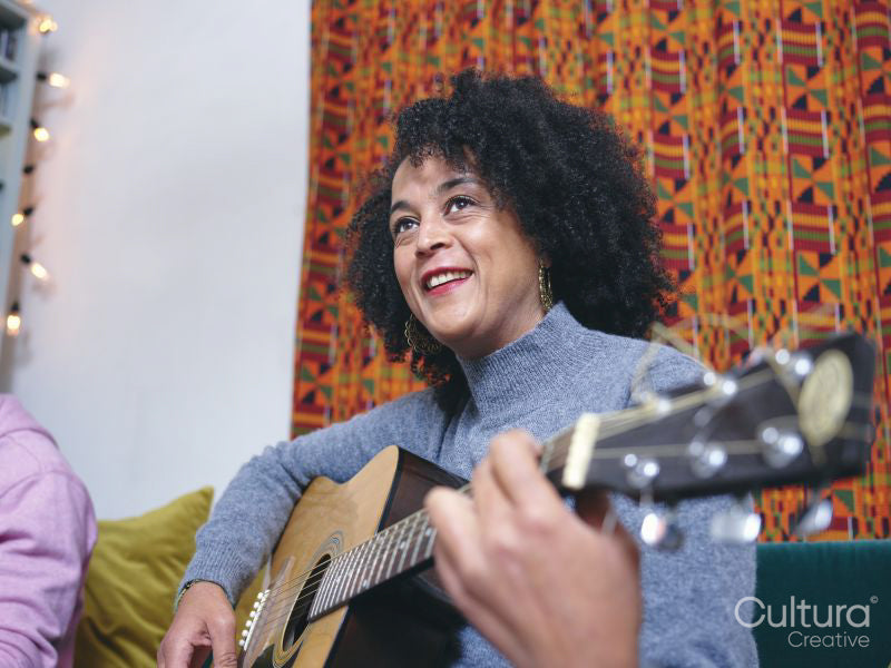 Woman playing acoustic guitar at home