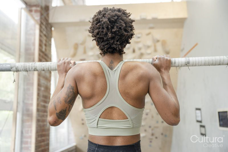 Woman performing chin-up exercise next to climbing wall