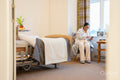 Senior lady using phone while sitting in bedroom at nursing home