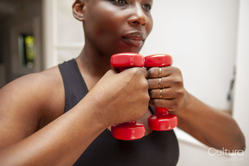 Mature woman exercising at home with dumbbells