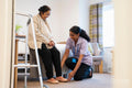 Nurse helping senior lady to put on her shoes at nursing home