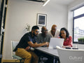 Colleagues looking at laptop during business meeting