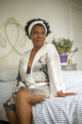 Woman wearing white headband and bathrobe sitting on bed