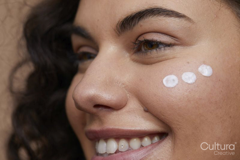 Close-up of young woman applying face cream