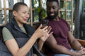 Smiling couple with smart phone relaxing in urban garden