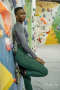Portrait of smiling athletic woman leaning on climbing wall at gym