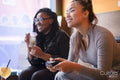 Female friends drinking cocktails and playing in video games at pub