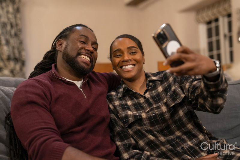 Mid adult couple taking selfie while sitting on sofa
