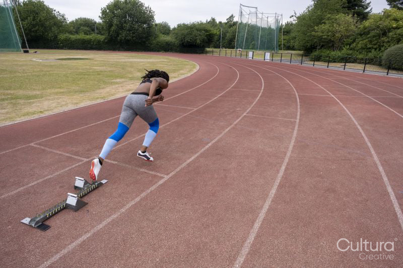 Rear view of athletic woman running on track