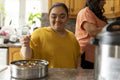 Woman with down syndrome adding spices while cooking with mother in kitchen