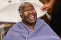 Smiling senior woman getting ready for hair wash in hair salon