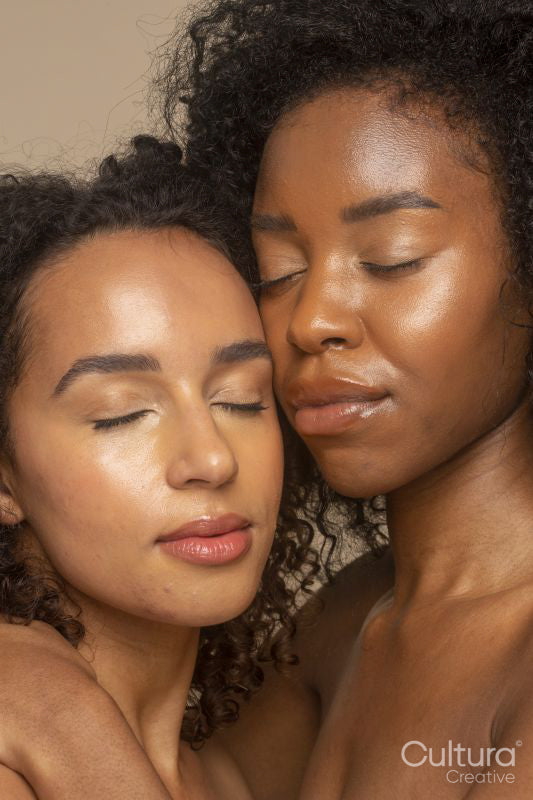 Studio portrait of two women with eyes closed cheek to cheek