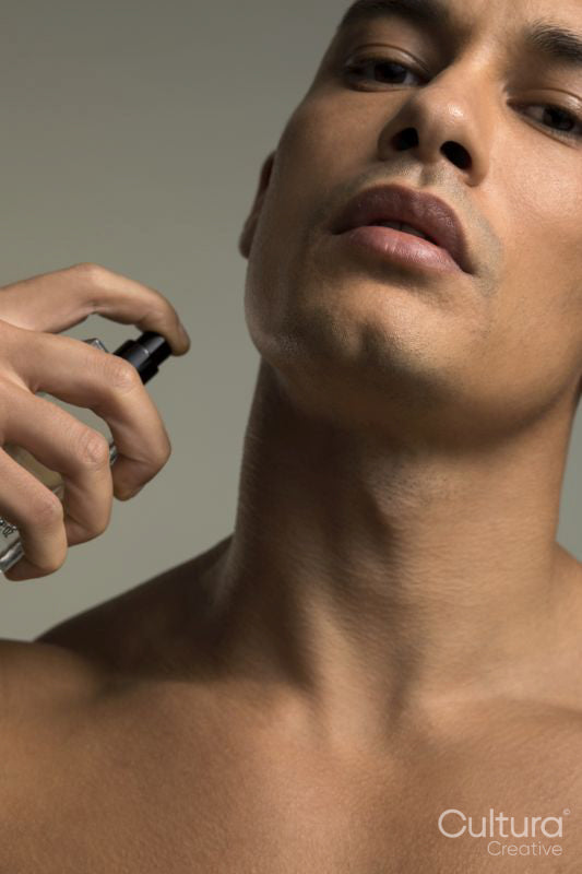 Close-up of man spraying perfume on neck