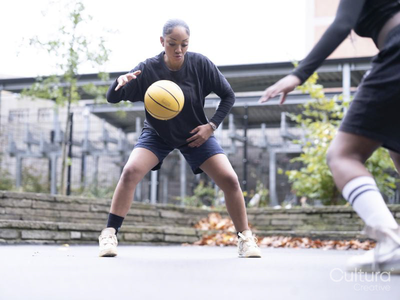 Two female friends playing basketball outdoors