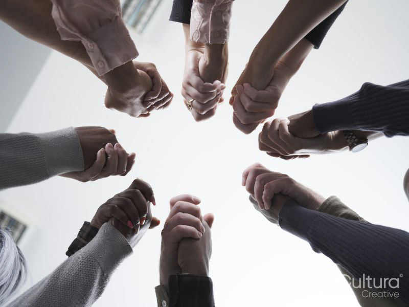 People stacking hands in circle in group therapy session