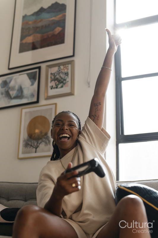 Excited young woman playing video games while sitting on sofa at home