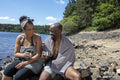 Smiling couple wrapped in towels enjoying tea on lakeshore, Yorkshire, UK
