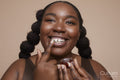 Studio shot of smiling young woman applying lip moisturizer