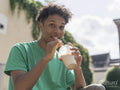 Portrait of young man drinking smoothie on sunny day