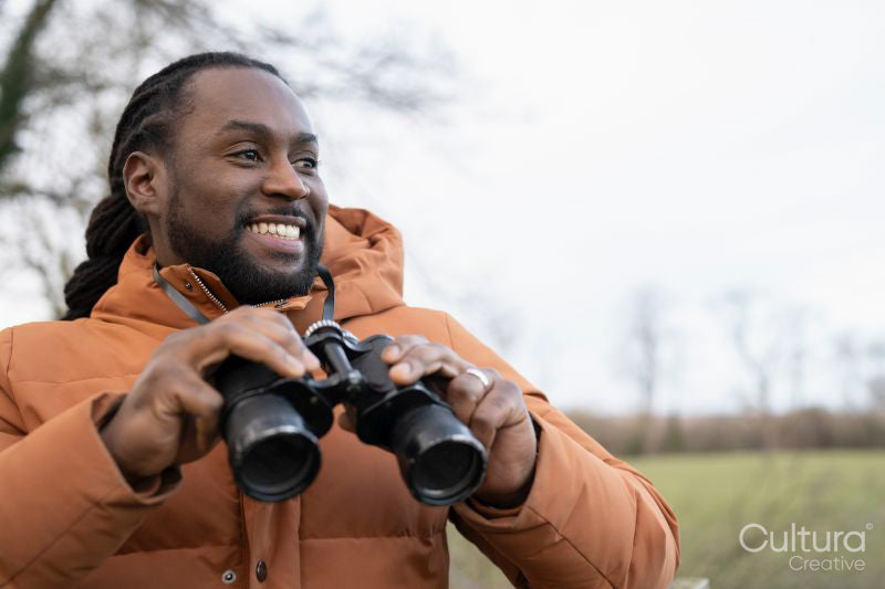Man looking through binoculars in rural area