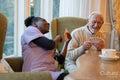 Smiling senior man and nurse playing cards at table in nursing home