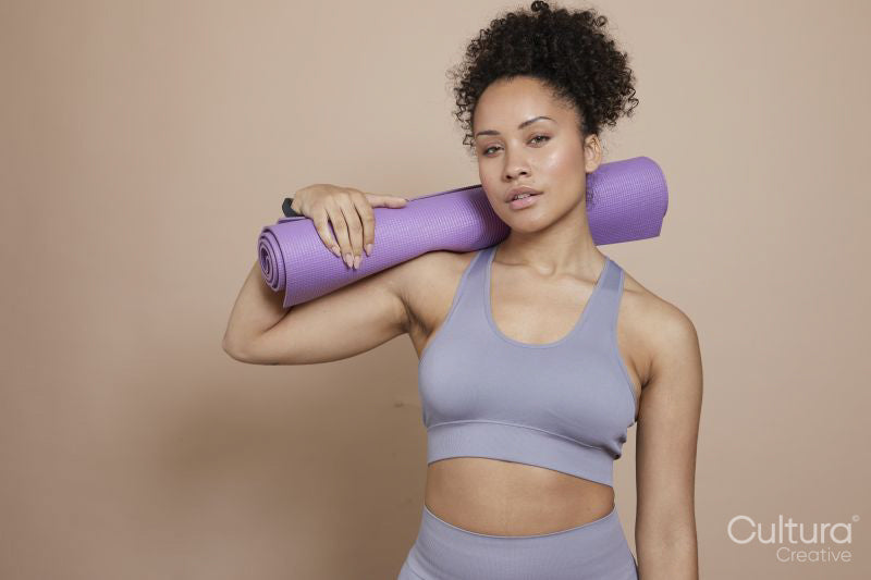 Studio portrait of athletic woman with yoga mat