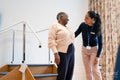 Smiling female therapist and senior woman talking in exercise room