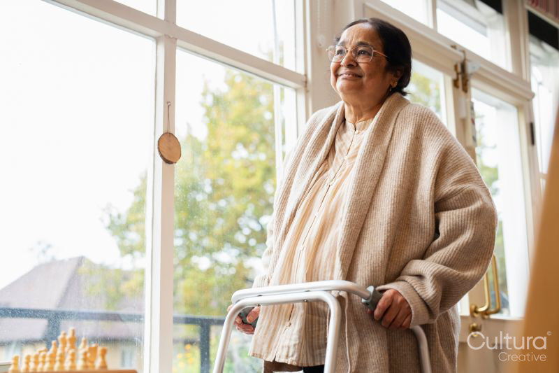 Senior woman wearing eyeglasses using mobility walker in nursing home