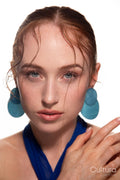 Studio portrait of a woman in a blue dress and large blue earrings
