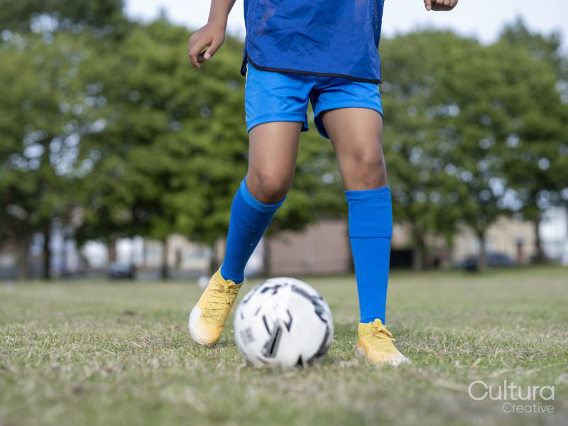 Low section of boy dressed in uniform practicing on soccer field