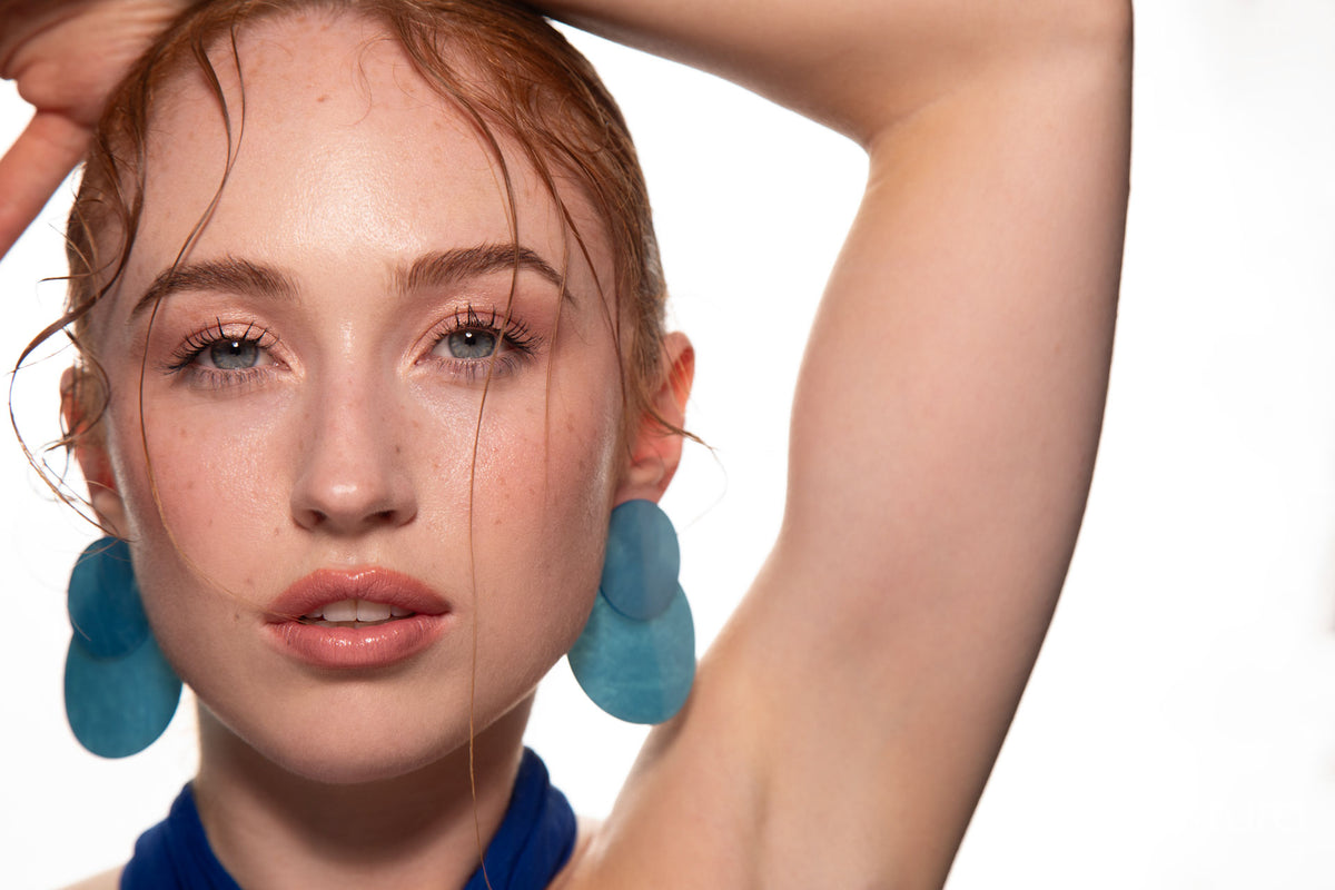 Studio portrait of a woman in a blue dress and large blue earrings