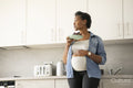 Pregnant woman holding plate with red grapes in kitchen